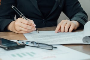 close-up-businesswoman-signing-terms-agreement-document-her-desk